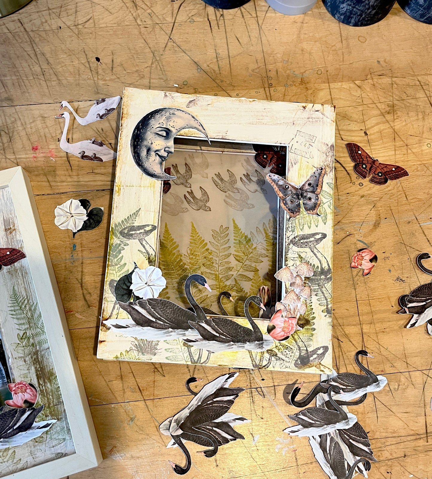 Collage of swans and nature elements on a wooden surface