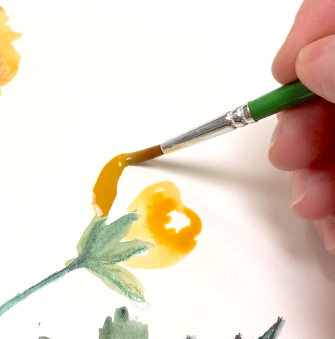 Hand painting a yellow flower with a green brush on a white background