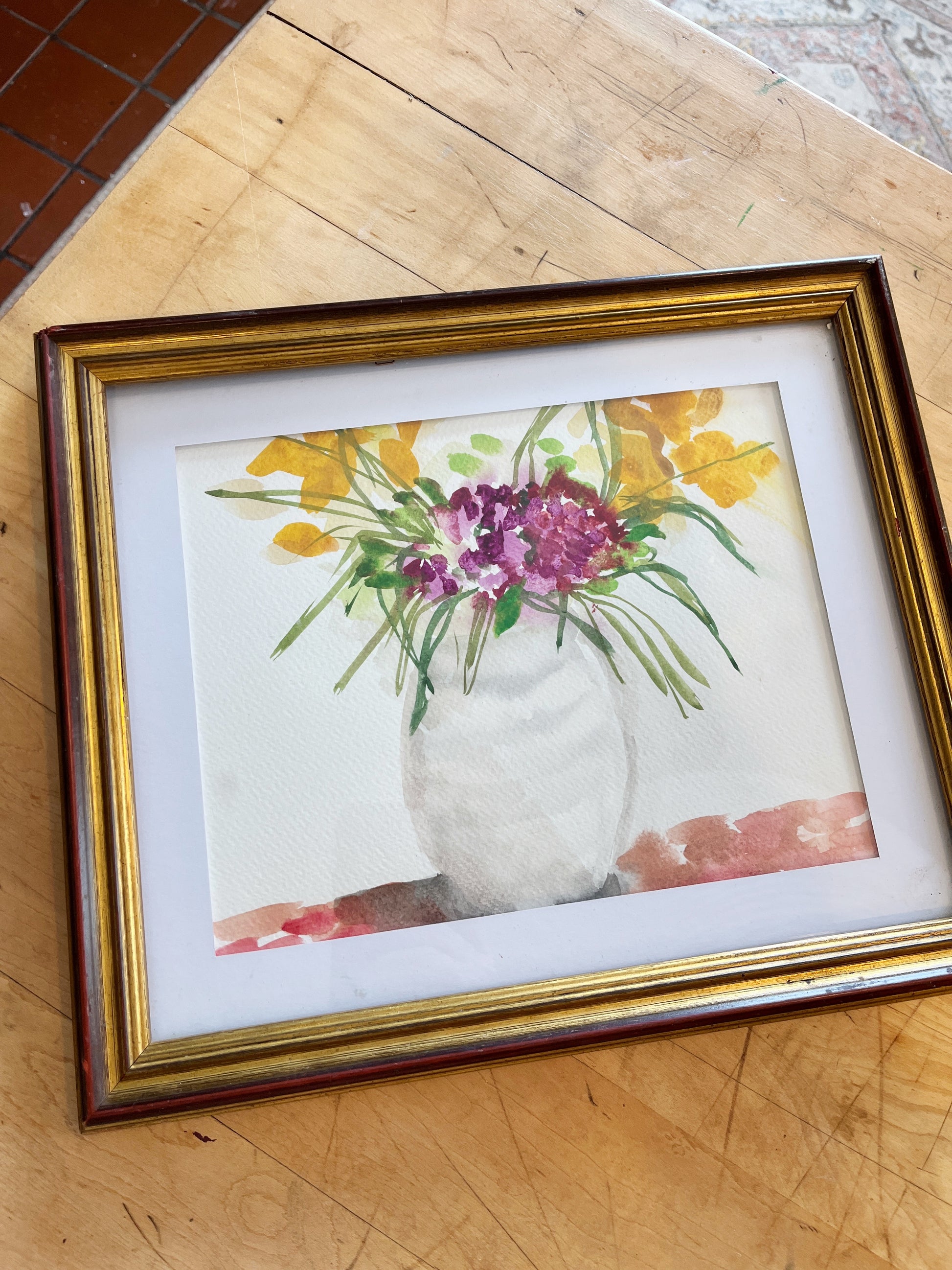 Framed artwork of a floral still life on a wooden surface